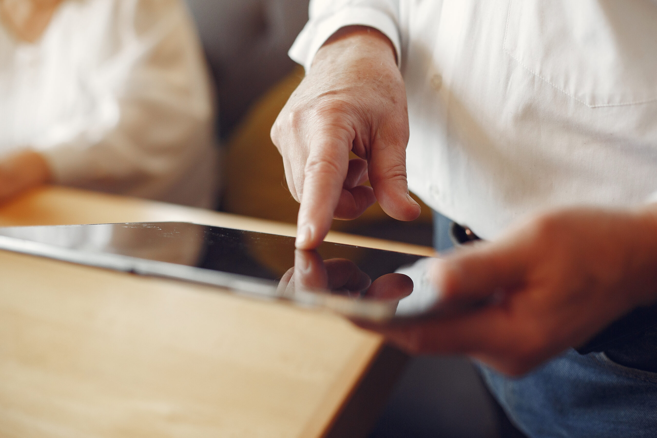 Close up of a hand with a finger touching the screen of a tablet device.