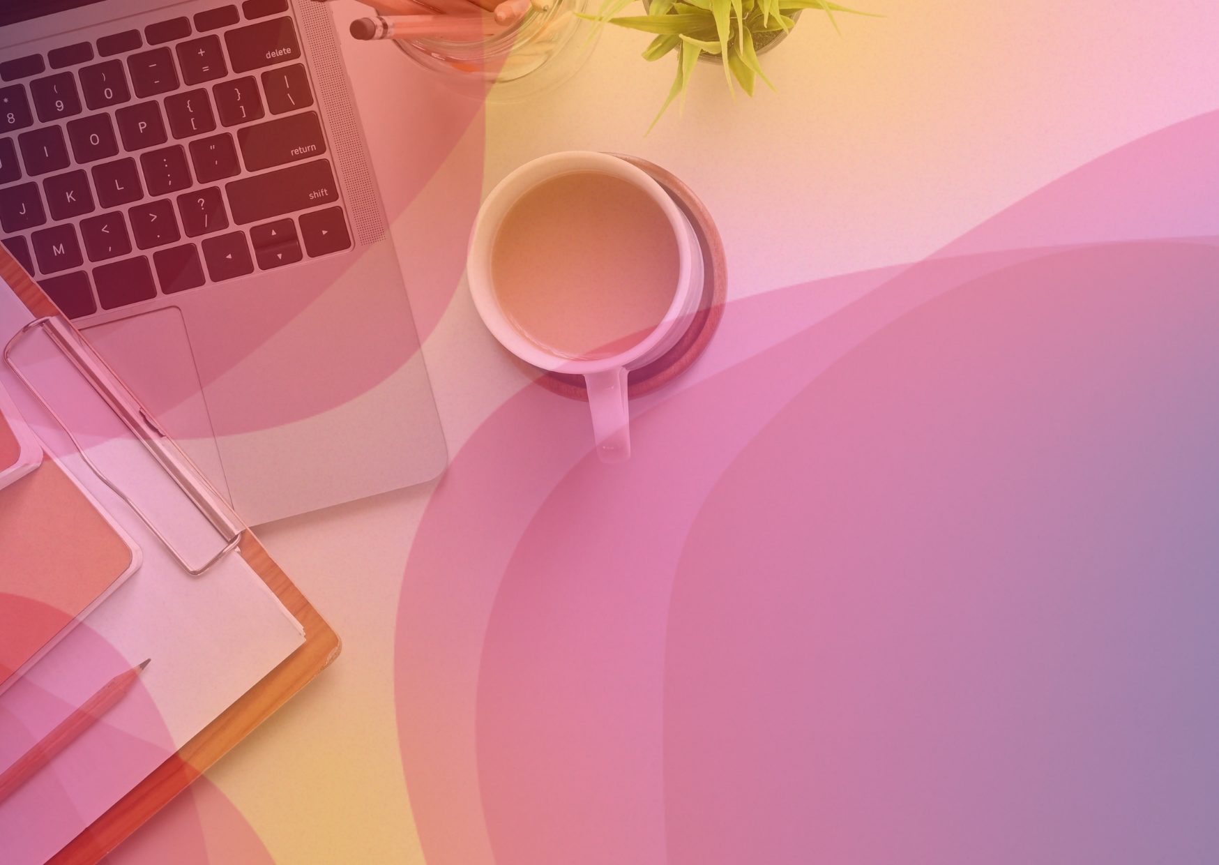 A desk with a laptop, notebook, and cup of tea.