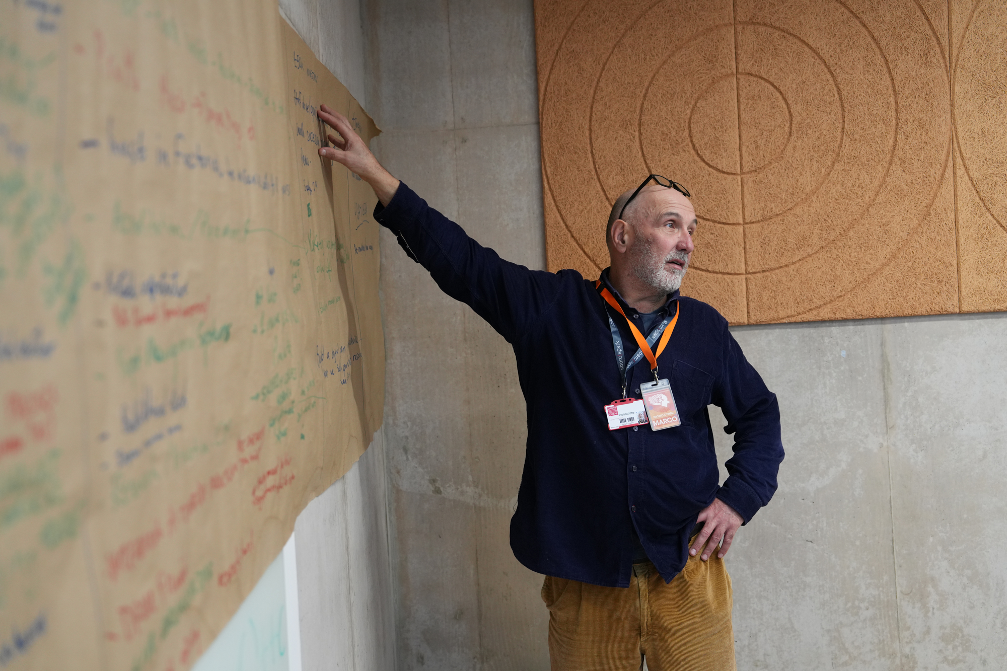 A man pointing to a wall with writing on it.