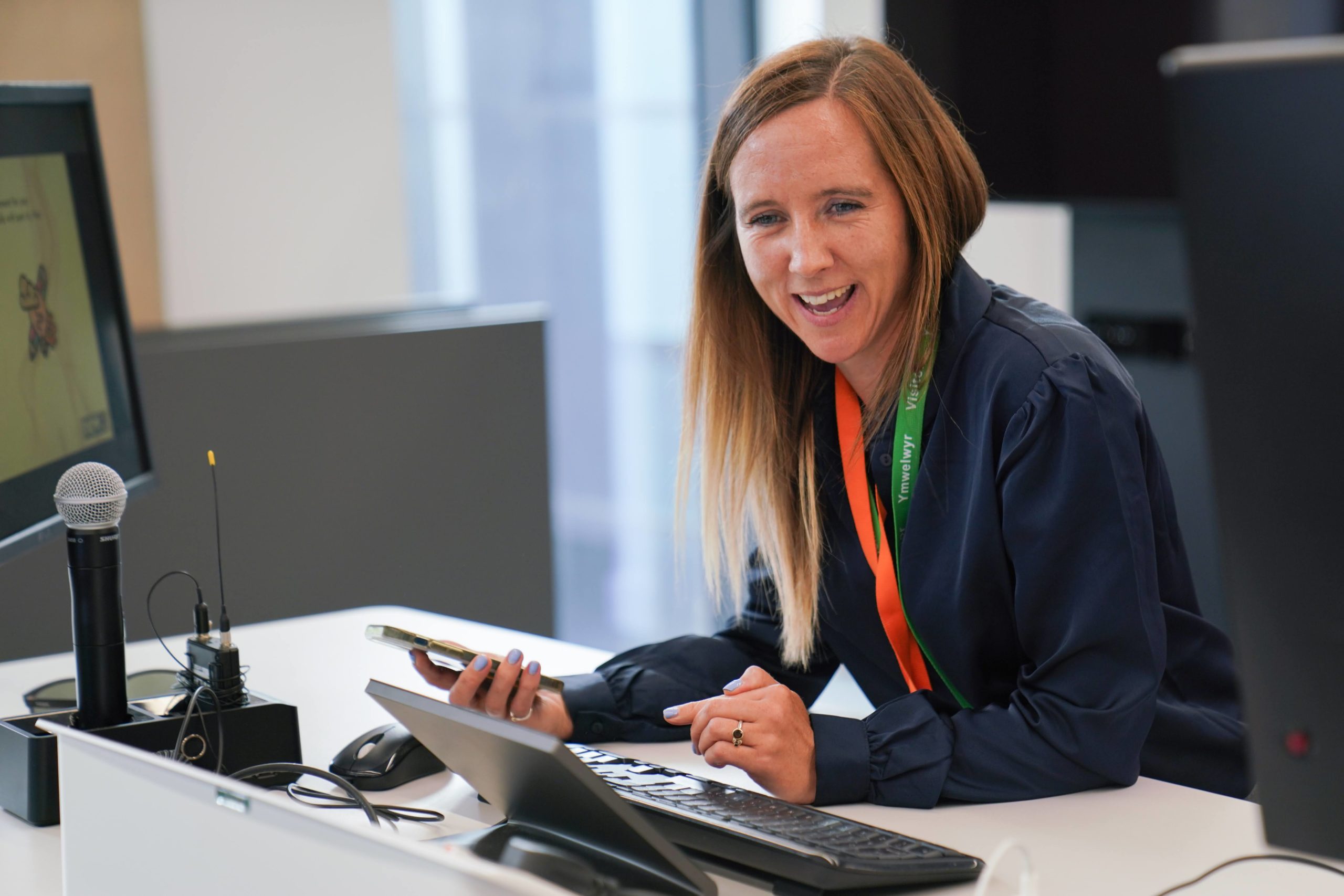 A woman working at a desk a phone in hand.