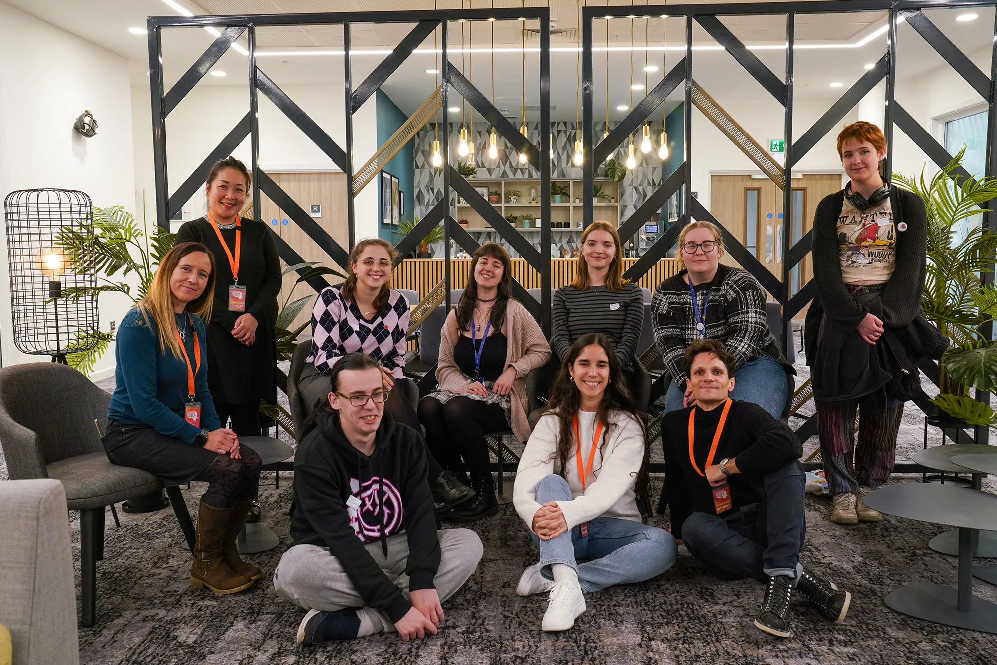 A diverse group of individuals smiling for a photo in front of a colourful backdrop.