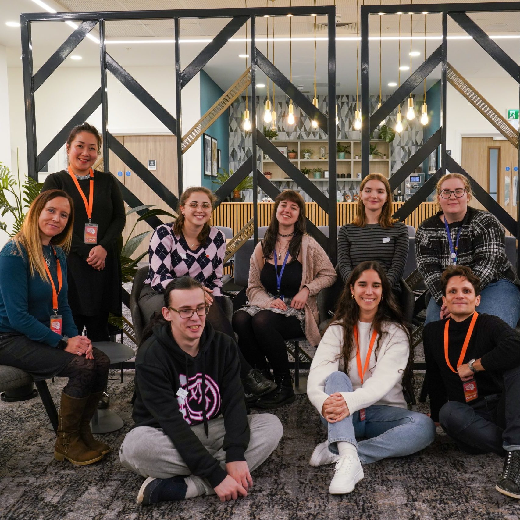 Group of young people sat on the carpet, smiling.