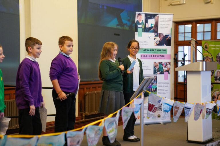 Children standing in front of a banner with a microphone, showcasing their talents.