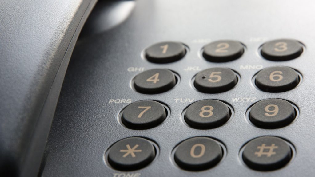 A close up of the numbers on a traditional office phone.