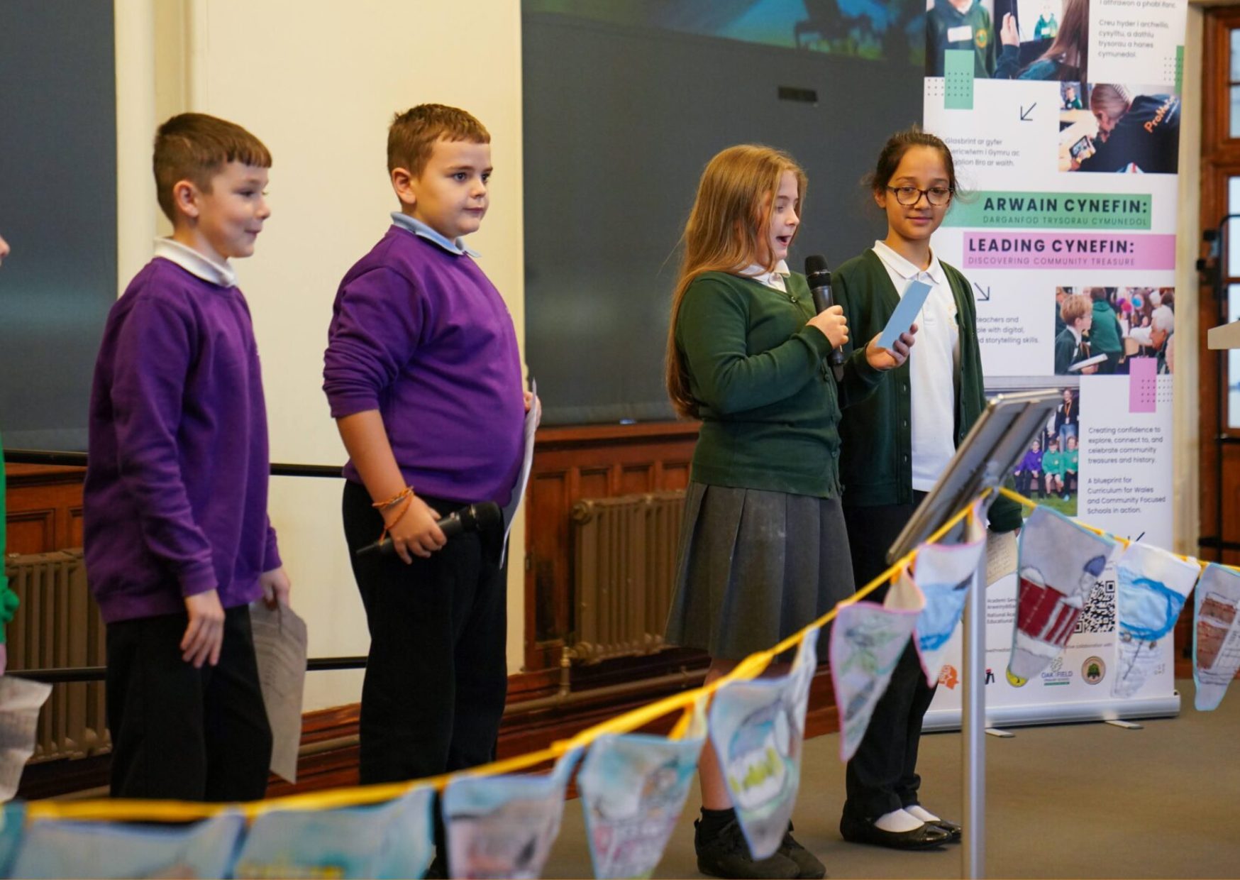 Primary school aged children talking into a microphone on stage