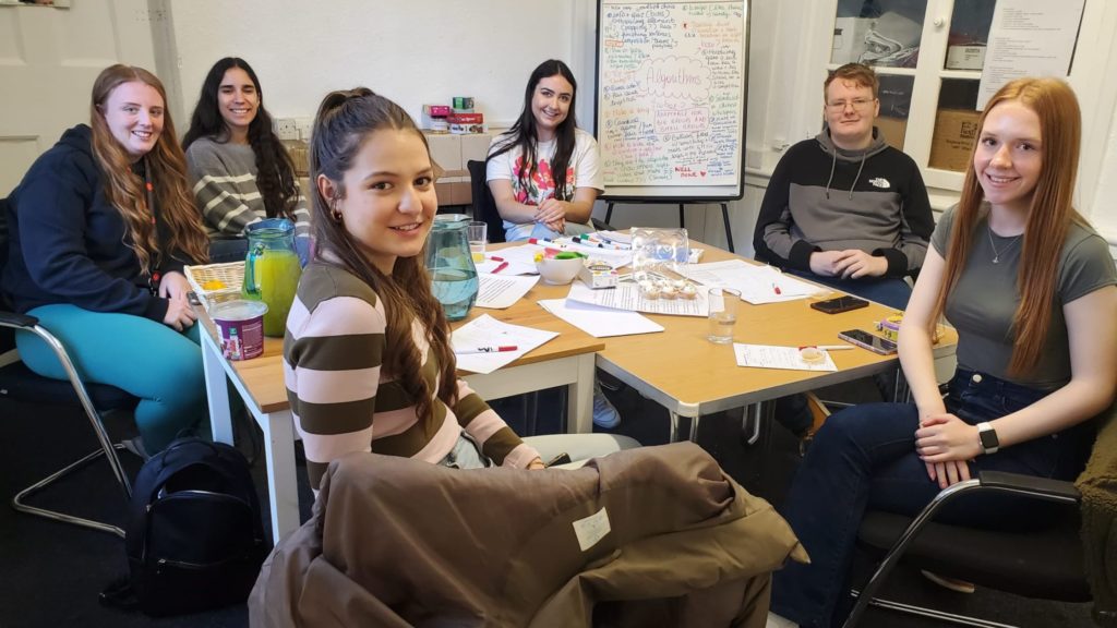 Group photo of staff members and young people sat around a table