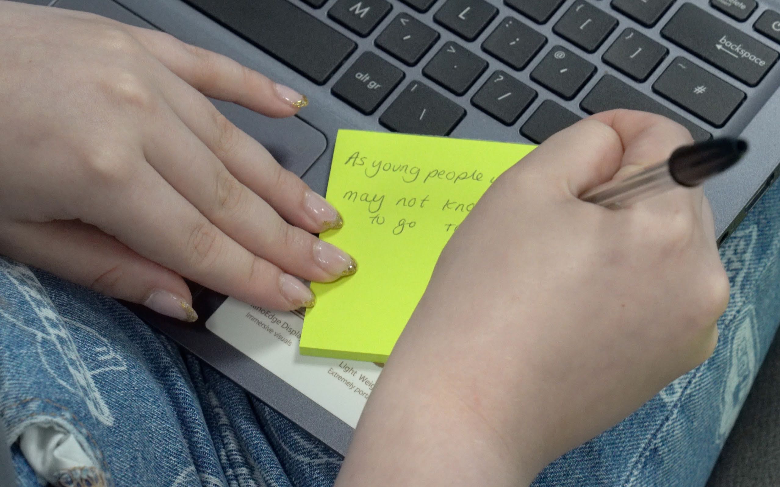 Close up photo of hands writing on a yellow post it