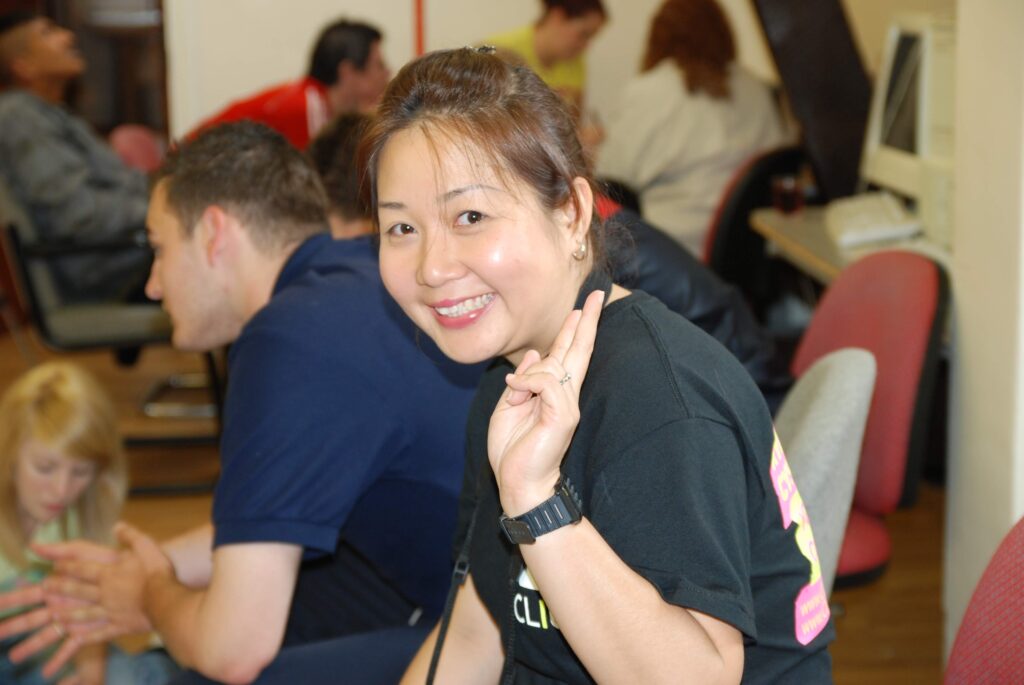 A young woman (Cindy) smiling at the camera with her fingers in a peace sign.