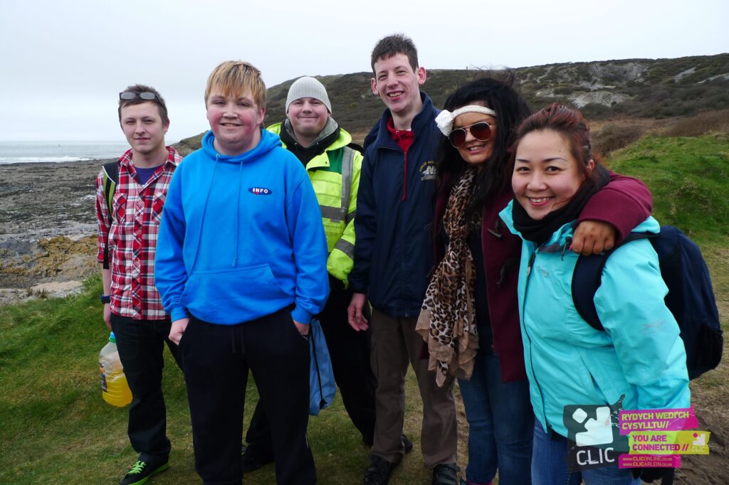 A group of 6 young people in hoodies and coats looking like they are on a walk in the countryside
